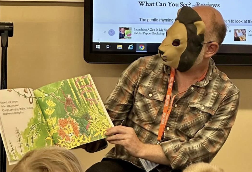 Jason looking remarkably like the lion in Hannah Rounding's jungle as he reads What Can You See? at South Street Primary in Gateshead